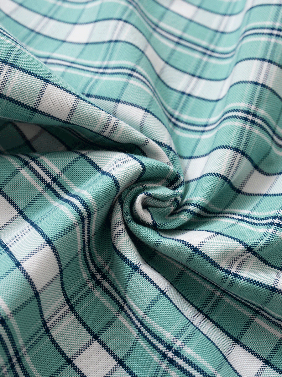 Close-up of the green plaid cotton Oxford fabric, showing its thick, full-bodied texture and weave used in mid-rise pyjama bottoms.