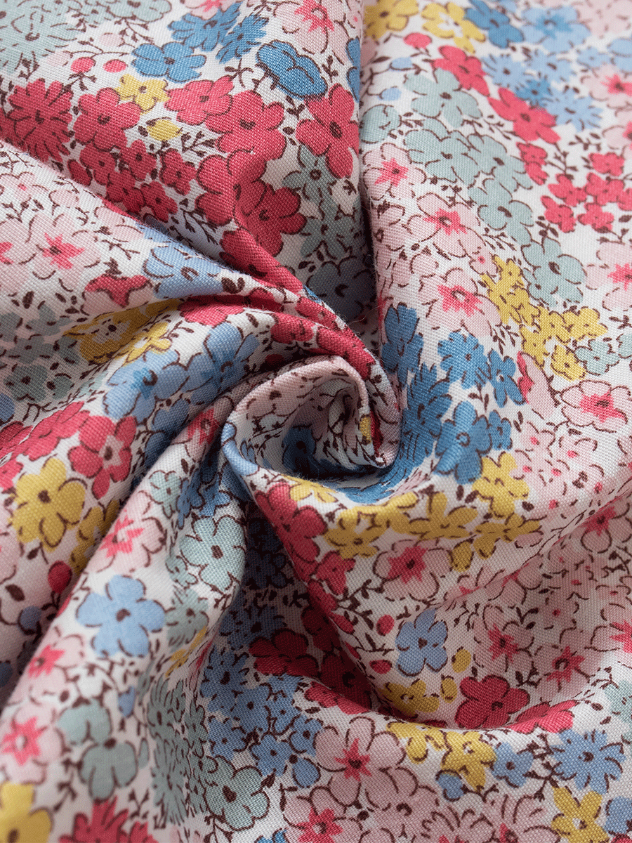 Detailed close-up of the fabric on low-rise lounge pants in a pastel pink ditsy floral print, showcasing vibrant red, blue, and yellow flowers on soft, breathable 100% cotton.