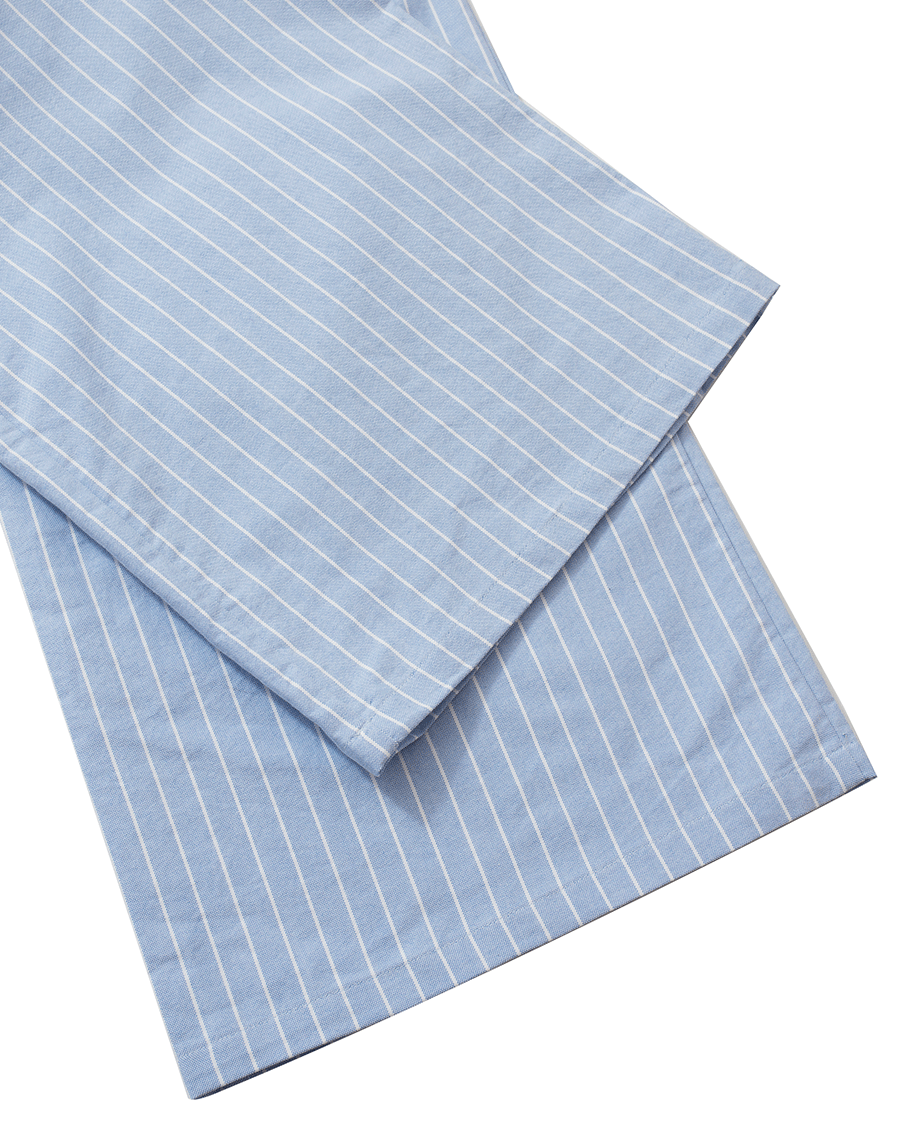 Close-up of the hem detail on low-rise wide-leg lounge pants in blue pinstripes, crafted from thick 100% cotton Oxford, showing clean edges and the fabric’s pattern.