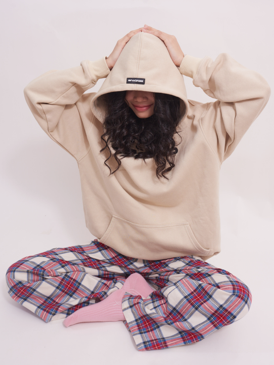 Model sitting cross-legged in low-rise wide leg lounge pants in red and cream plaid tartan, showing the relaxed fit and soft texture, ideal for casual or sleepwear.