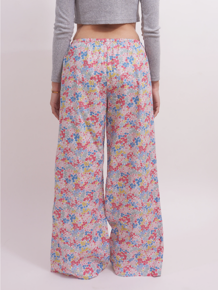 
                                            
                                                Back view of low-rise wide leg lounge pants in pastel pink ditsy floral print, showing a relaxed fit perfect for lounging or sleepwear. Made from 100% cotton for breathable comfort.
                                            
                                        