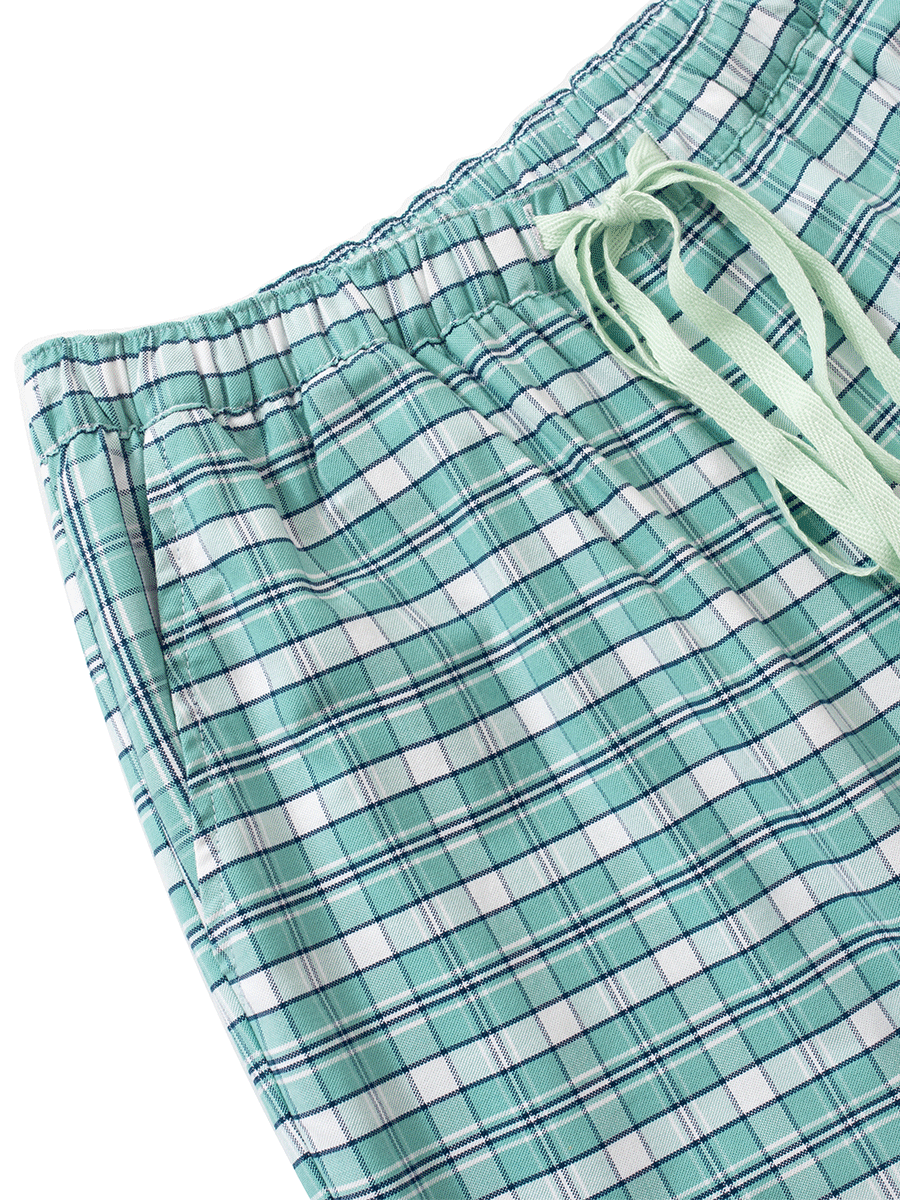 Waist detail of mid-rise pyjama bottoms in green plaid, featuring an elastic waistband with a matching drawstring for comfort and fit, side pockets, and crafted from thick cotton Oxford.