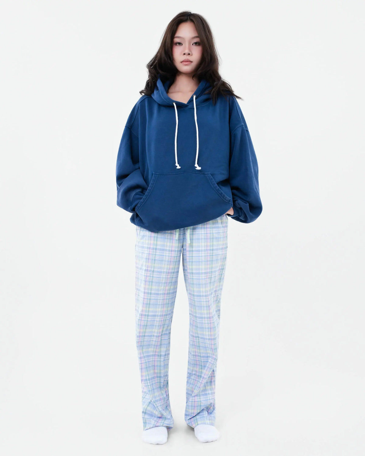 Model wearing powder blue and pink tartan plaid pyjama bottoms with a blue hoodie