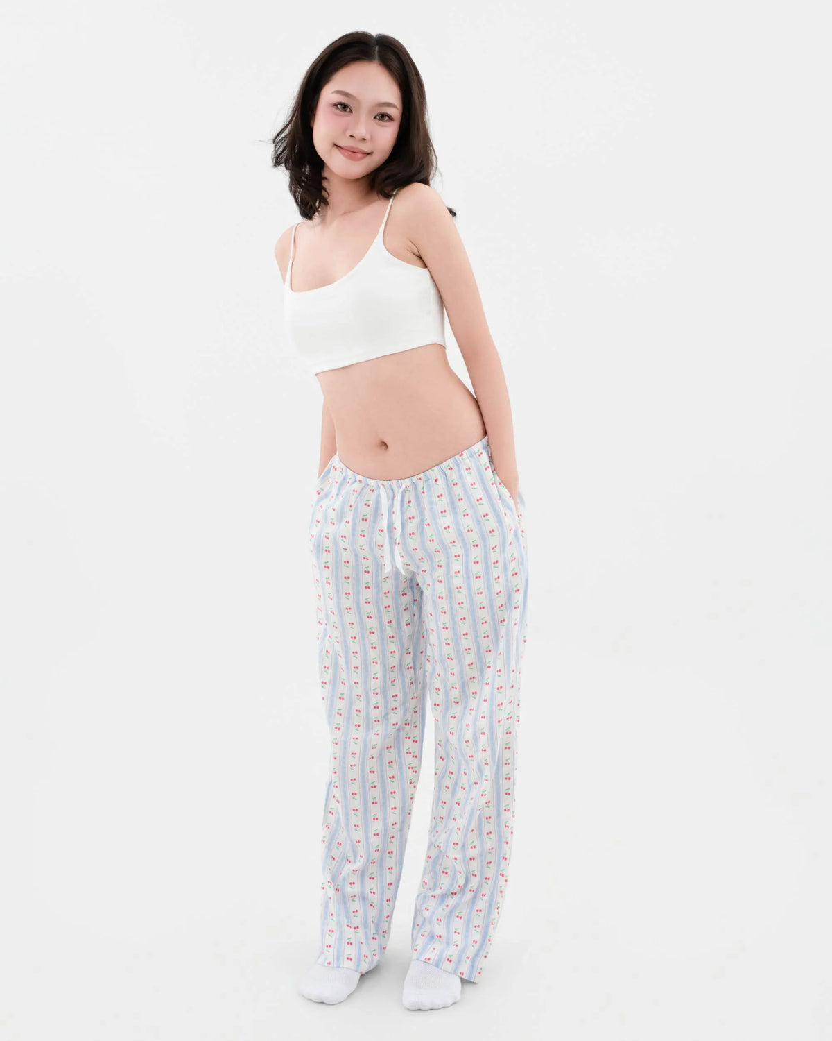 Model wearing Lounge Low Rise cherry-print blue-stripe linen pyjama bottoms from the front