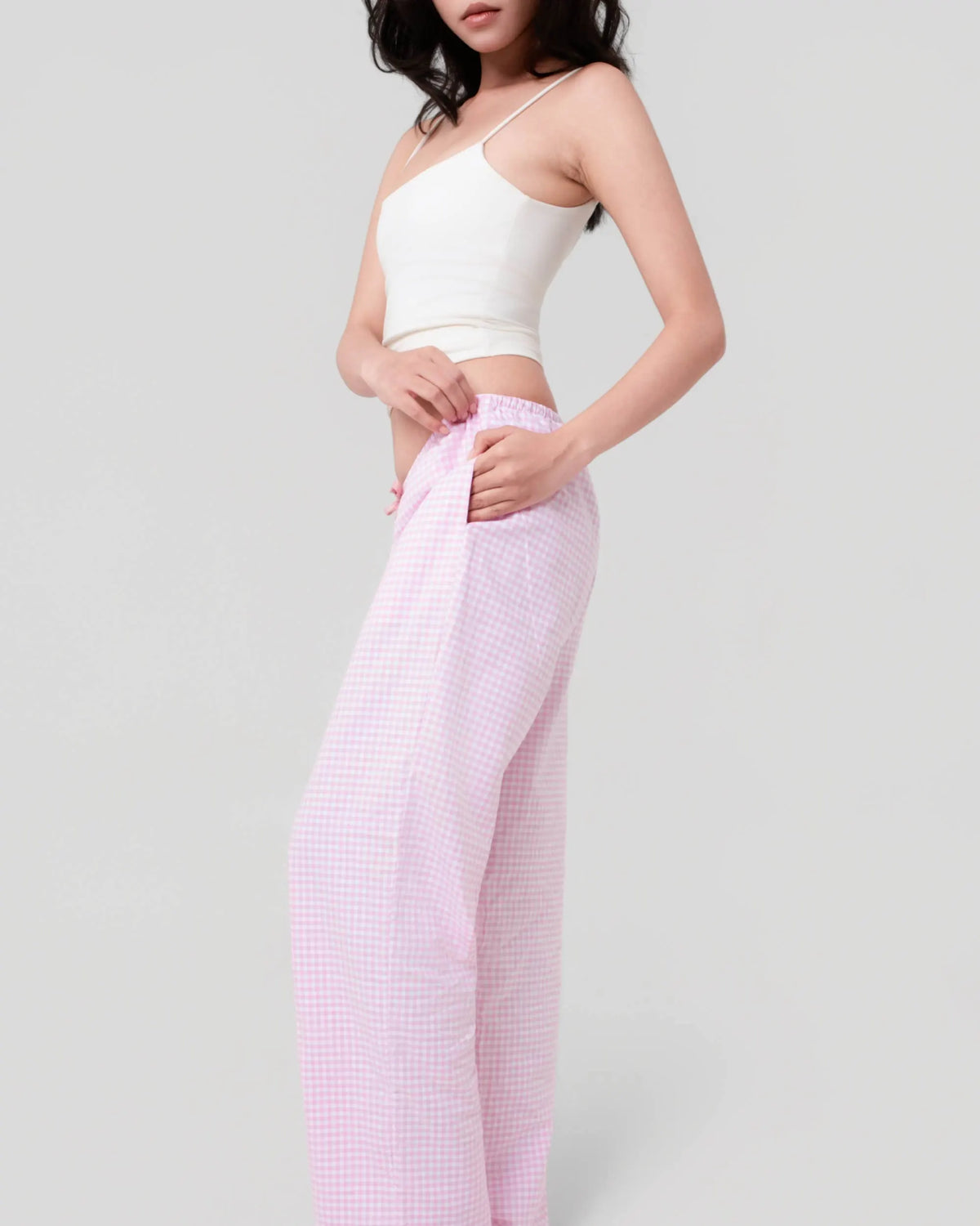 Side view of pink and white gingham cotton Oxford pyjama bottoms showing the low-rise waist and pocket