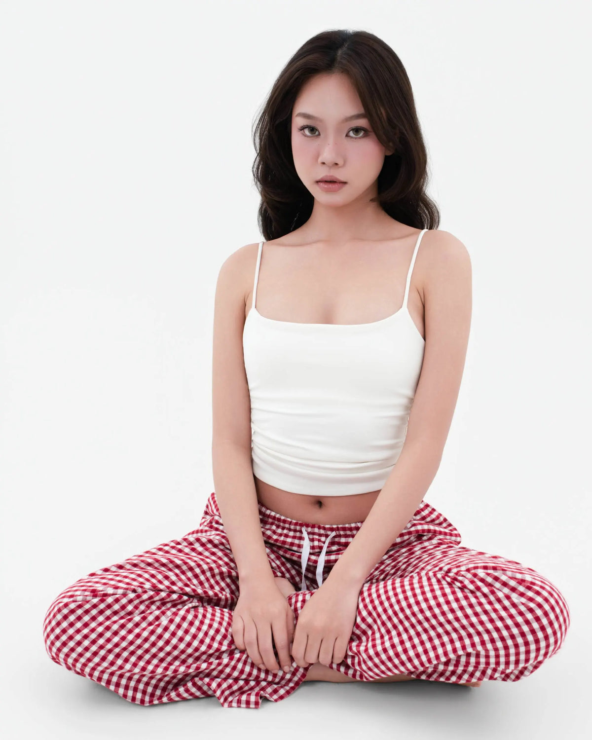 Model seated cross-legged in SleepyPants Lounge Low Rise red and white gingham flannel pyjama bottoms